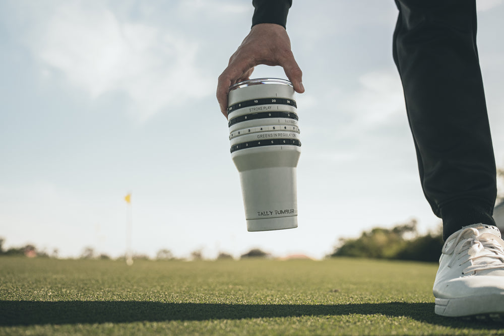 Person holding a insulated tumbler on a golf course