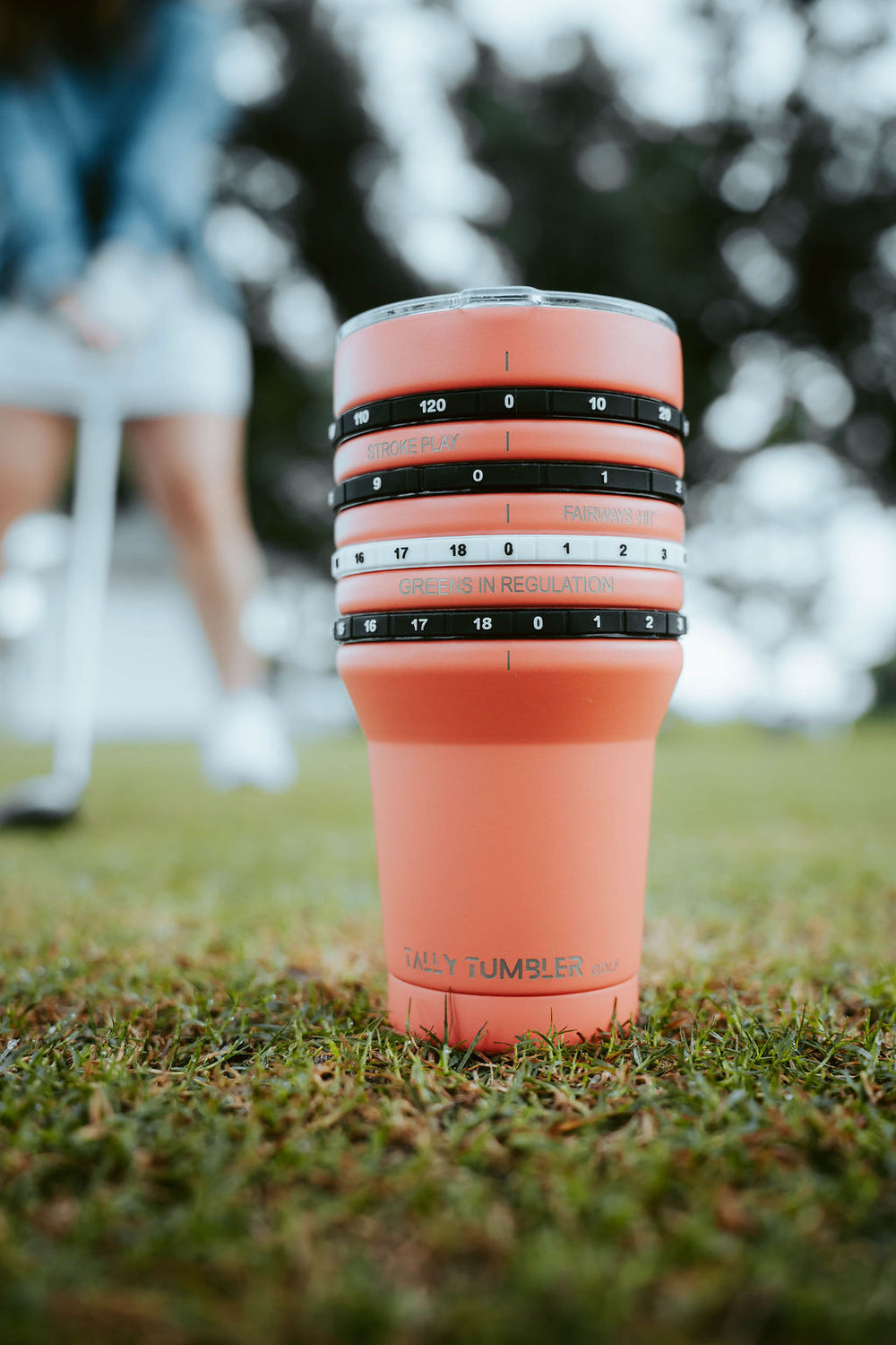 Pink insulated tumbler with measurement markings on grass